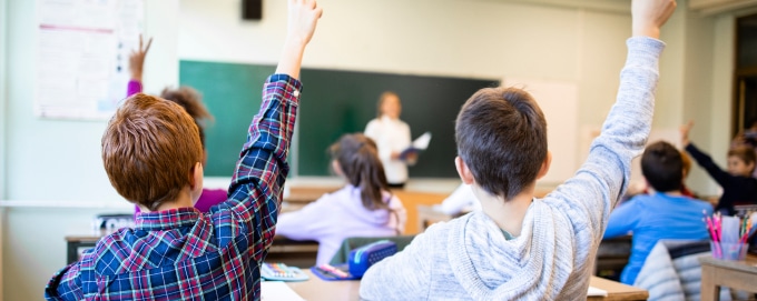 Children raising hands in classroom