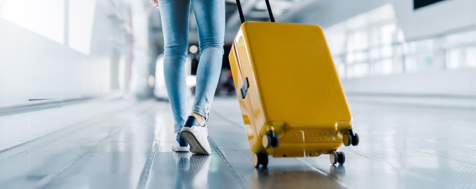 Person wheeling suitcase down airport concourse