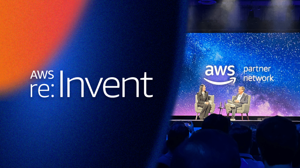 re:invent logo on gradient background featuring a photo of speakers presenting at an event