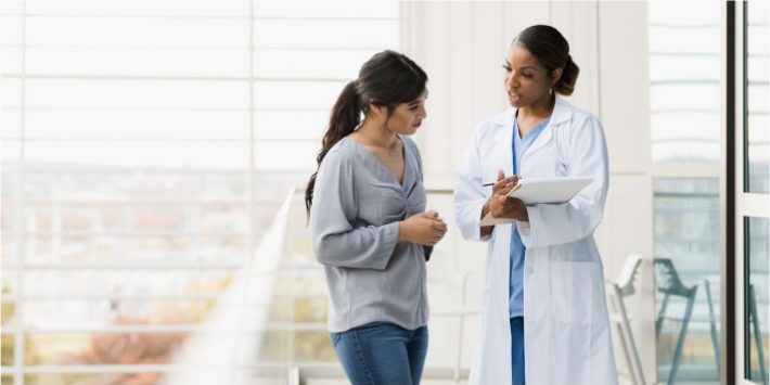 Doctor and her patient standing next to each other having a conversation