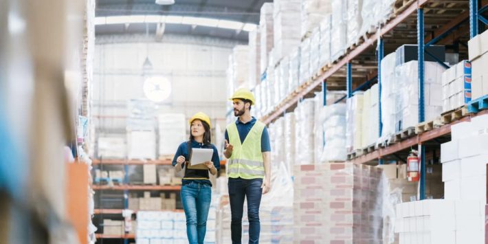 Male and female workers discussing over stock checklist in warehouse
